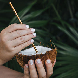 hands painted with coconut non toxic nail polish holding a coconut