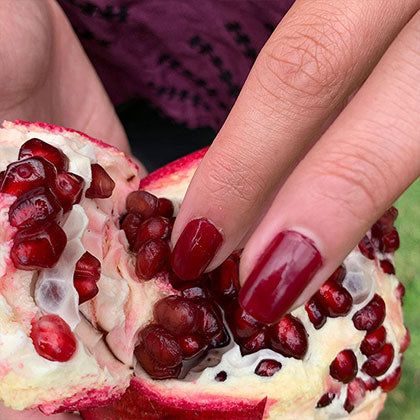hand pealing pomegranate wearing nohea natural nail polish