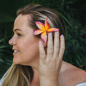 Wahine wearing strawberry guava non toxic nail polish holding a flower